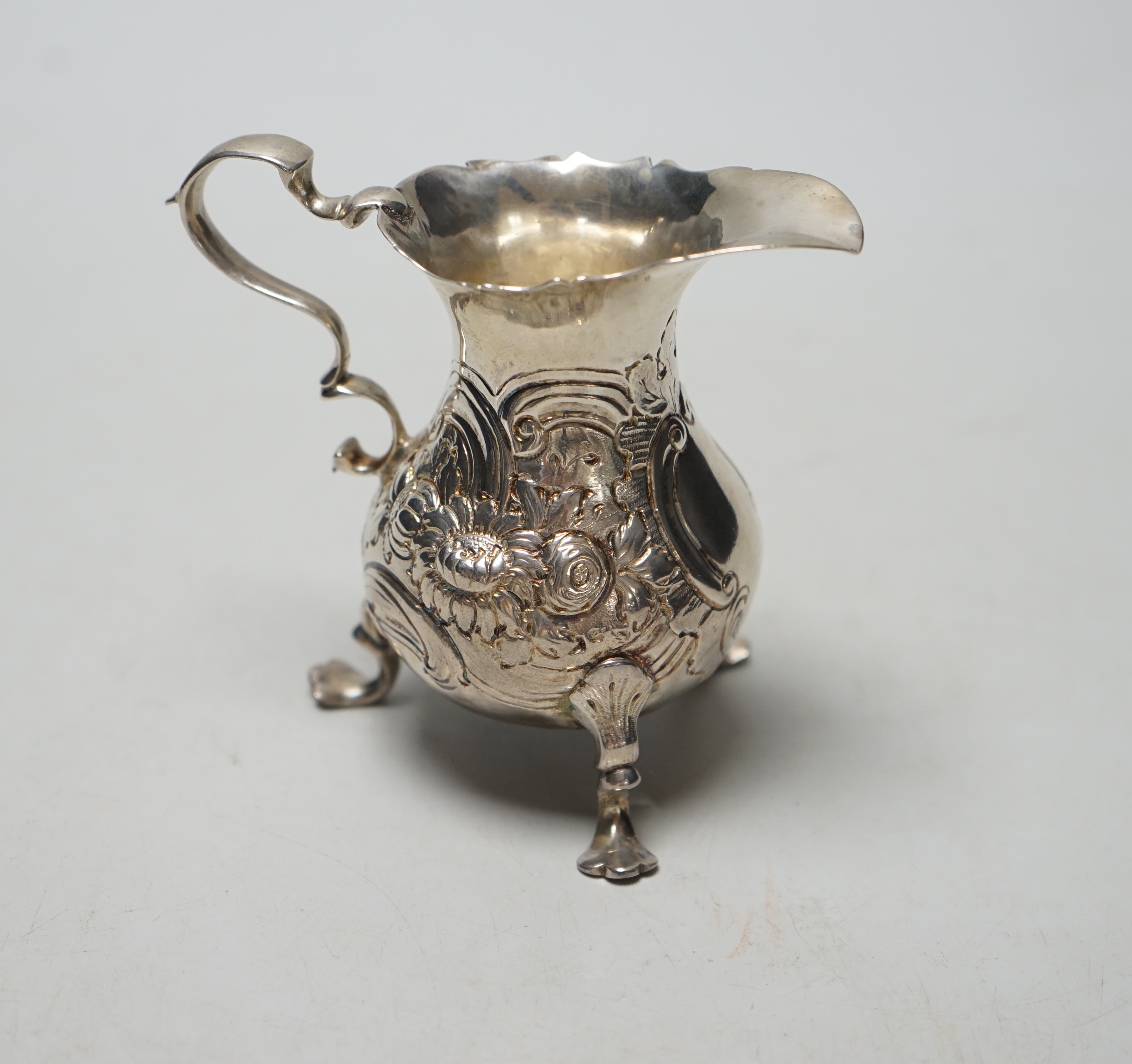 A George II silver cream jug, with later embossed decoration, marks rubbed, London, 1750? (a.f.), height 89mm, 77 grams.